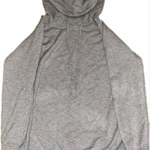 Grå hoodie - Säljer en stilren grå hoodie med långa ärmar och justerbar huva. Perfekt för en avslappnad look. Den har ribbade muddar vid ärmslut och nederkant för extra komfort.