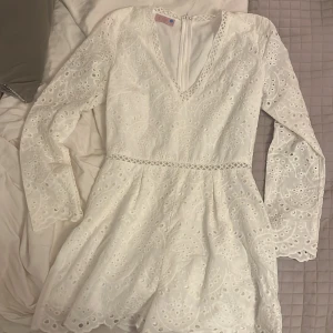 Vit spetbyxdress från Noella Fashion - Säljer en vacker vit byxdress från Noella Fashion med spetsdetaljer och v-ringning med långa ärmar och en dragkedja i ryggen. Perfekt för sommarens festligheter! Storlek S, men liten i storleken tyvärr så därför jag säljer❣️skulle säga den är som en XS! Skriv för frågor 