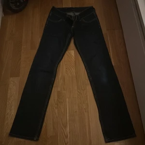 Mörkblå jeans med broderade bakfickor - Snygga mörkblå låg midjade jeans med broderade detaljer på bakfickorna. Dom har  en rak passform. Perfekta för en stilren look. 