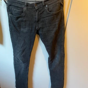 Svarta jeans från Replay - Snygga svarta jeans från Replay med klassisk femficksdesign. De har en knappgylf och är tillverkade i ett slitstarkt denimtyg. Perfekta för en stilren look.