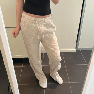 Beige linnebyxor med snörning - Säljer ett par bekväma beige linnebyxor med elastisk midja och snörning. Perfekta för en avslappnad stil.