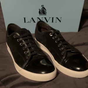 Svarta sneakers från Lanvin - Snygga svarta sneakers från Lanvin med en stilren design. Skorna har en blank tå och snörning framtill. Perfekta för en trendig look.