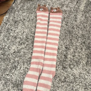 Kawaii/Cutecore strumpor med björnar - Säljer ett par supermysiga knästrumpor i rosa och vit randigt mönster. Strumporna har en söt björndetalj högst upp med små öron. Perfekta för att hålla värmen och se gullig ut samtidigt!