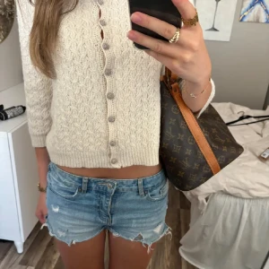 Beige stickad kofta från By Malene Birger - Säljer en elegant beige stickad kofta från By Malene Birger. Koftan har ett vackert mönster och knappar framtill. Perfekt för kyliga dagar och ger en stilren look.