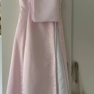 Ljusrosa balklänning med pärldetaljer - Elegant ljusrosa balklänning med vackra  blommor av pärlor längs sidan. Klänningen har en snörning på sidan för justerbar passform och en axelbandslös design. Klänningen är ifrån France Mode i strl M😍