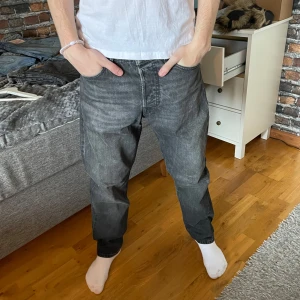 Svarta jeans från Jack and Jones  - Säljer ett par svarta jeans från Jack and Jones i storlek W30 L32. De har en klassisk femficksdesign och en normal passform. Perfekta för en avslappnad stil. Lagat ett hål se på sista bilden 