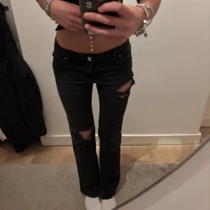 Svarta slitna bootcut jeans - Lågmidjade svarta jeans med coola slitningar! 