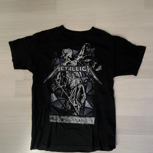 Svart Metallica t-shirt med tryck - Svart vintage t-shirt med ikoniskt Metallica-tryck framtill, coolt motiv i grått och vitt. Storlek M/L, pris 200 kr 