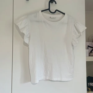 Vit blus med volangärmar🤍 - Supersöt vit blus från Kappahl med korta volangärmar och rund halsringning. Tillverkad i mjuk bomull som känns skön mot huden. Perfekt för dig som gillar en enkel men ändå söt stil med extra detalj på ärmarna🫶🏻