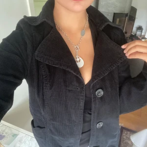 Svart manchesterkappa  - Säljer en svart lång kappa i manchester. Perfekt för dig som gillar en stilren och tidlös look! Strl 40 men passar 100% en 38:a! 