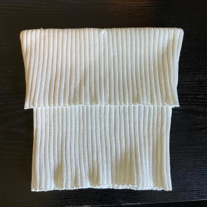 Vit ribbad bandeau tubtopp från Zara - Säljer en vit ribbad bandeau tubtopp från Zara. Toppen är ärmlös och har en tight passform med breda ribbade ränder som ger en snygg struktur.