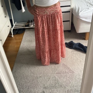 Rosa långkjol med paisleymönster från Zara - Supersnygg långkjol från Zara i rosa med vitt paisleymönster och broderade detaljer i midjan. säljs då den inte riktigt kommer till andvändning, andvänd kanske 3 gånger.