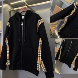 Svart hoodie med Burberry-rutor - Svart hoodie från Burberry med klassiska beige, röda och svarta rutiga paneler längs ärmarna. Tröjan har huva med snörning, dragkedja framtill och stora fickor. Perfekt för dig som gillar streetstyle med lyxig touch. Koftan är i Storlek M och är helt ny säljer för att jag köpte fel storlek. 