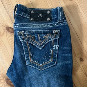 Miss Me jeans  - Snygga blå jeans från Miss Me med broderade bakfickor, nitar och dekorativa sömmar. Bootcut-modell med låg midja. Säljer då de tyvärr inte passar längre