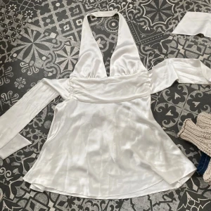 Vit klänning i satin - Supersnygg vit känning  i glansigt satinmaterial med djup v-ringning och långa ärmar. ☀️Använd 1 gång.