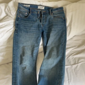 Jack & Jones Slim Glenn jeans - Snygga blå jeans från Jack & Jones, modell Slim Glenn. Jeansen har en slim passform, klassisk femficksdesign och knäppning med knappar. Tillverkade i mjukt denim med snygg tvätt och kontrastsömmar. Perfekta för en clean och stilren look.