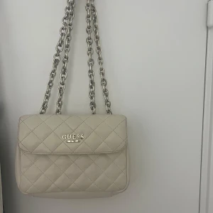 Beige quiltad axelväska från Guess - Säljer en beige quiltad axelväska från Guess den är helt som ny är knappt andvänd 