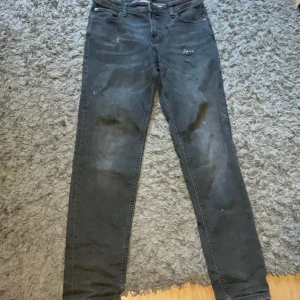 Grå slim jeans Jack & Jones - Slim Glenn jeans från Jack & Jones i mörkgrå tvätt. Klassisk femficksmodell med smal passform och normal midja. Jeansen är tillverkade i bomull med en snygg, något sliten look och diskreta slitningar framtill.  Priset går att diskutera vid snabb äffar 