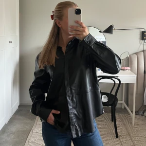 Svart overshirt i fakeskinn  - Något mindre i storleken och har en loose fot