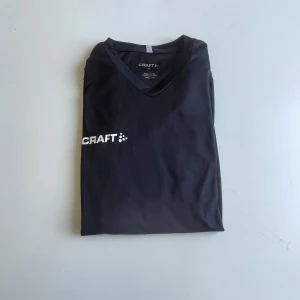 Svart långärmad träningströja Craft - .Häll dig bekväm och stilren under träning eller till vardags med denna svarta Craft träningströja med läng ärm. Designad för en aktiv livsstil, med funktionella egenskaper som passar perfekt för löpning, gym eller fritid.  Märke: CRAFT Storlek: Medium (M) Färg: Svart Material: Lätt och andningsbart funktionsmaterial