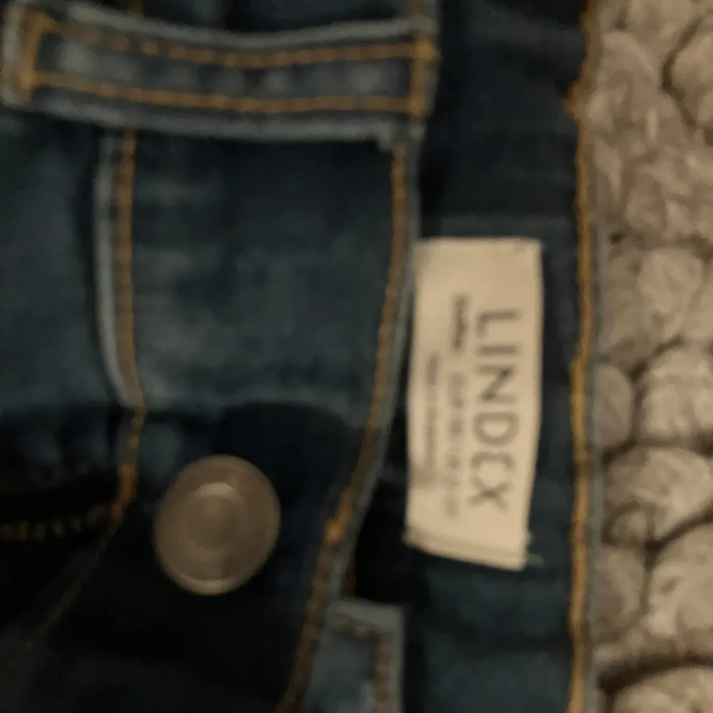 Snygga blå jeansshorts från Lindex med klassisk design och knappstängning. Perfekta för en avslappnad stil under varma dagar.. Shortsit.