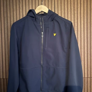 Mörkblå jacka med dragkedja - Snygg mörkblå jacka från Lyle & Scott med dragkedja och huva. Den är perfekt till vår och sommar 