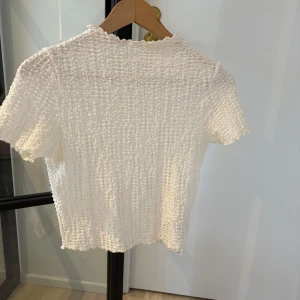 Vit ribbad topp - Säljer en söt vit ribbad topp från FB Sister. Toppen har korta ärmar och en fin struktur. 