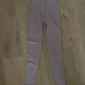 Lila ribbade leggings - Snygga lila leggings med ribbad struktur och hög midja. Perfekta för en bekväm och stilren look. Passar bra till både träning och avslappnade dagar.