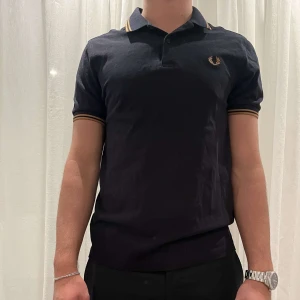 pikétröja från Fred Perry - Säljer en snygg mörkblå piké från Fred Perry!! Stilren och snygg Piké med klassisk stil, skicket är så gott som nytt!! Inhandlades ny för 1000kr, säljer nu för 389kr!! Storlek M Slim!! Sitter som S/M! 