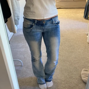 Blå jeans från Dromedar - Snygga blå jeans från Dromedar och dekorativa nitar vid fickorna. Köpt tidigare här på Plick! Den tidigare ägaren har sprättat upp kanten på Jensen som ni kan se på bild 2! Skriv om ni fundera på något!🩷Midjemått 36 men stretchiga, längd 73 men dom är uppsprätade så kanske 76! 