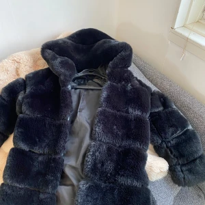 Svart pälsjacka från Philinzo - Snygg och lyxig svart pälsjacka från fhilunio. Jackan har en elegant design med långa ärmar och en mjuk, fluffig textur. Perfekt för att hålla sig varm och stilren under kyliga dagar.