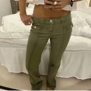 Gröna byxor med fickdetaljer - Snygga gröna byxor med bootcut-stil och dekorativa fickor framtill. Byxorna har en låg midja och är tillverkade i ett bekvämt material. Perfekta för en avslappnad look. (Första bilden är lånad) mått: midja: 33, innerben: 80