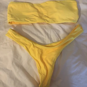 Gul bikini med bandeau-topp - Snygg gul bikini med en stilren bandeau-topp och matchande botten. Perfekt för soliga dagar på stranden eller vid poolen. Enkel och modern design som ger en fräsch look🌼