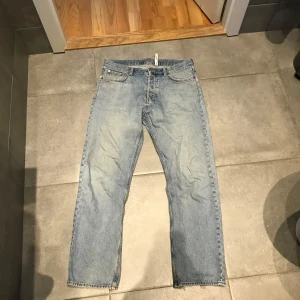 Blå jeans från Weekday - Säljer ett par blå jeans från Weekday i modellen Space Relaxed Straight. De har en klassisk femficksdesign och en knappgylf. Perfekta för en avslappnad stil.