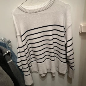 Vit och svart randig tröja från 157 - Säljer en stilren vit tröja med svarta ränder från 157. Tröjan har en ribbad rund hals och långa ärmar, perfekt för en avslappnad look. Passar bra till både jeans och kjol.