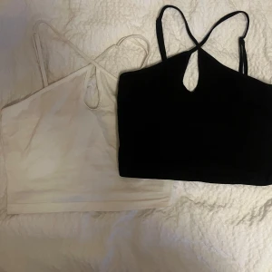 Svart och vit linnetopp - Två stilrena linnetoppar i svart och vitt med smala axelband och en liten öppning framtill. Perfekta för en avslappnad look eller att styla upp med accessoarer.