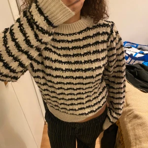 Randig stickad tröja från MNG - Säljer en oanvänd mysig stickad tröja från MNG i beige och svart. Tröjan har ett randigt mönster och långa ärmar. Perfekt för kyliga dagar!