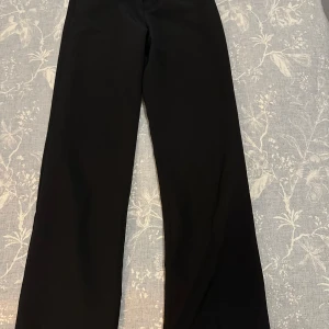 Svarta kostymbyxor från Lindex - Snygga svarta kostymbyxor från Lindex med en klassisk design. Byxorna har en rak passform och är utrustade med knappar och hällor för bälte. Perfekta för en stilren look.