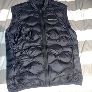Svart dunväst från Peak Performance - Säljer en svart dunväst från Peak Performance med dragkedja. Den har två hål vid bröstet som är lagat med laglapp hos skräddare men de syns knappt 😁 Som ny annars. 