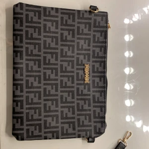 Svart och grå axelväska med mönster - Snygg axelväska i svart och grått med ett stilrent mönster. Väskan har en praktisk dragkedja och en justerbar axelrem. Perfekt för att bära dina nödvändigheter med stil. Nästan aldrig andvänt haft ca 1,5 År.  