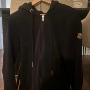 Marinblå zip hoodie från Moncler - Snygg marinblå zip hoodie från Moncler med ribbade muddar med röd och vit detalj. Mycket gott skick. Storlek L. Passar M.  