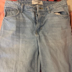 Ljusa low wasited jeans med wide fit  - Säljer ett par ljusa jeans med wide fit och låg midja. De har en klassisk  dragkedja med knapp framtill. Perfekta för en avslappnad stil. Passar mig som är storlek 38, men sitter lite oversized. Storlek:40 ej använda så mycket men har lite slitage i benen(se bild 2), därav priset.