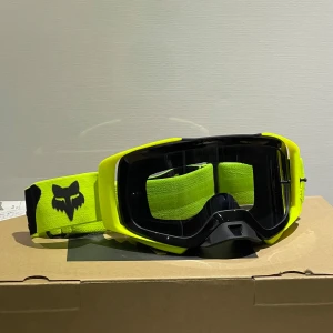 Fox racing airspace goggles - Säljer ett par neongula motocrossglasögon från Fox med svart logga på bandet. Glasögonen har svart ram och justerbart band. Extra grönt glas och vit påse för förvaring medföljer.