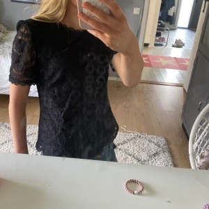 Svart spetsblus från märket Pieces - Säljer en svart blus från Pieces i storlek XS. Blusen är helspets med korta ärmar och rund halsringning, samt fina spetsdetaljer längs kanterna. Perfekt för sommaren