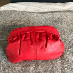 Röd axelväska i skinn - Säljer en snygg röd axelväska i skinn med mjuk, rundad form och veckade detaljer framtill. Väskan har ett stort fack och stängs med tryckknapp. Perfekt för att addera färg till din outfit!😁❤️Öppen för prisförslag!