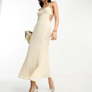 Midiklänning i beige/vit från ASOS helt ny - Säljer en elegant långklänning i en beige/vit färg med smala axelband och öppen rygg. Klänningen har en figurnära passform upptill och faller snyggt längs kroppen. Perfekt för bal eller fest. Materialet känns lätt och svalt. Helt ny med alla lappar kvar! 