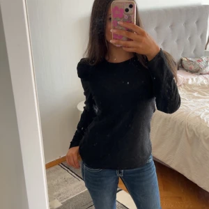 Svart långärmad glitter topp med puffärm - Säljer en svart långärmad topp med puffärmar och rund halsringning. Toppen är i ett mjukt, stretchigt material och har en slim passform som sitter snyggt på kroppen. Perfekt att styla med jeans eller kjol.