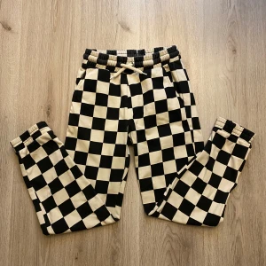 Svartvita rutiga mjukisbyxor - Säljer ett par mjuka och bekväma mjukisbyxor från Lindex i storlek 146/152. Byxorna har ett svartvitt rutigt mönster, resår och snörning i midjan samt muddar vid bensluten. Skriv om du har frågor o läs gärna min bio innan du köper🫶🏻✨
