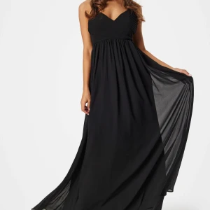 Svart balklänning v-ring öppen rygg  - Balklänning svart med smala axelband, v-ringad fram. Öppen rygg med korsade band. Passar till festliga tillfällen. ALDRIG ANVÄND, lapp kvar. Skicka om du vill ha fler bilder, mått osv!