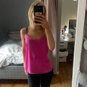 Rosa linnetopp - Säljer en snygg rosa linnetopp med smala axelband och djup v-ringning. Perfekt för varma dagar eller som ett lager under en jacka. Enkel och stilren design som passar till mycket.